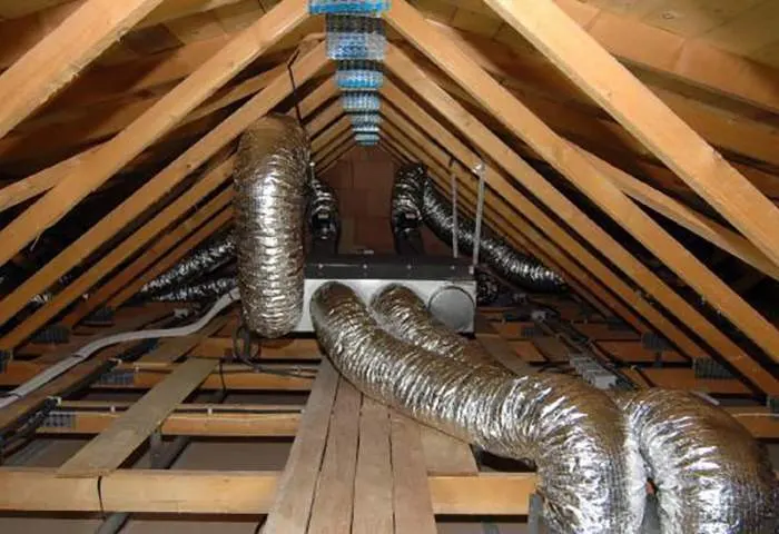 Installateur ayant posé un réseau de gaines de gainable dans des combles